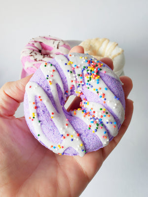Purple raspberry vanilla vegan donut bath bombs with cocoa butter icing and rainbow sprinkles