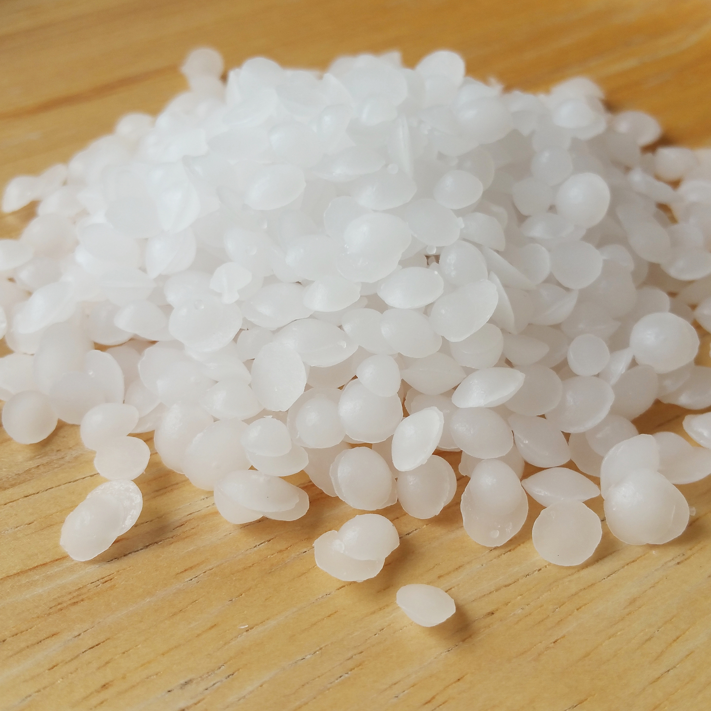 White emulsifying wax pellets on a wooden surface