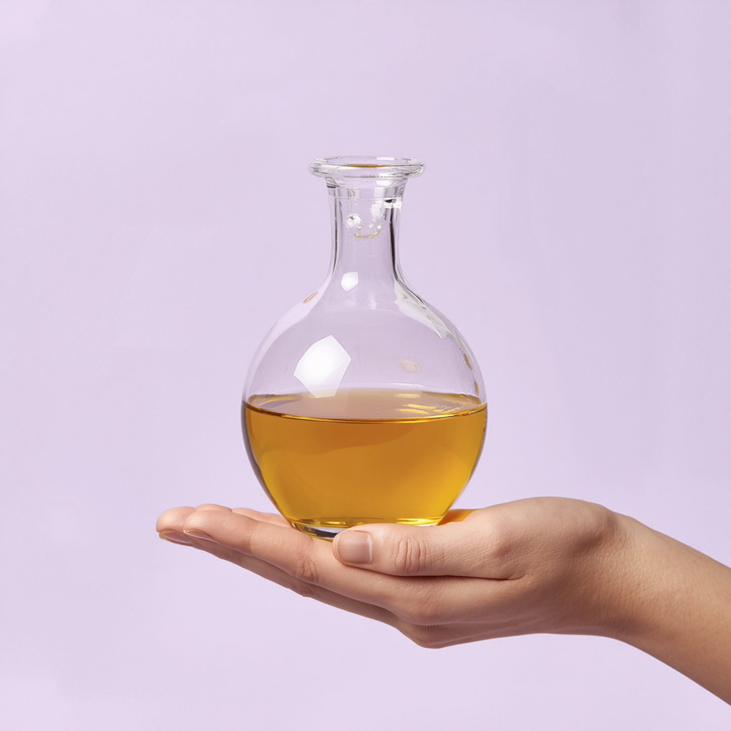 Hand holding a glass container with yellow liquid against a light purple background