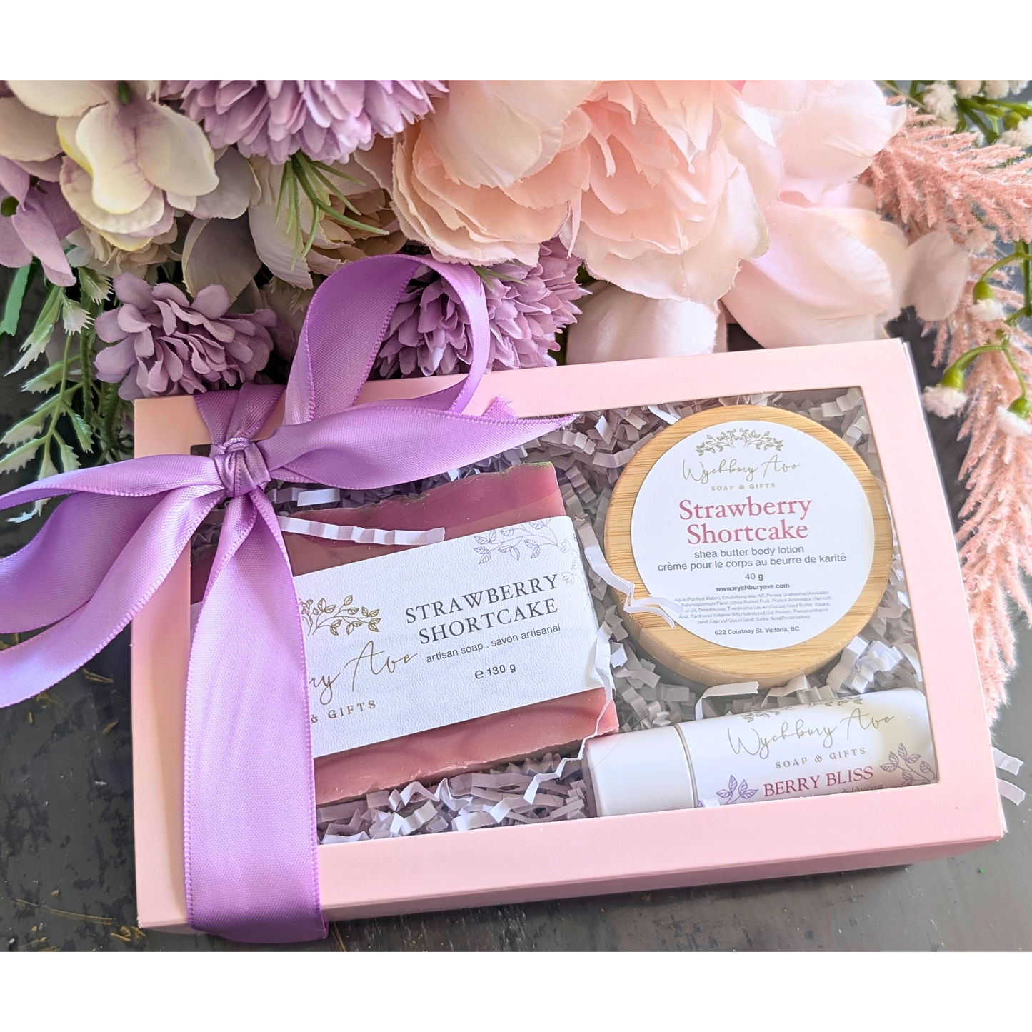 Gift set with strawberry shortcake flavor label, pink ribbon, and flowers in the background