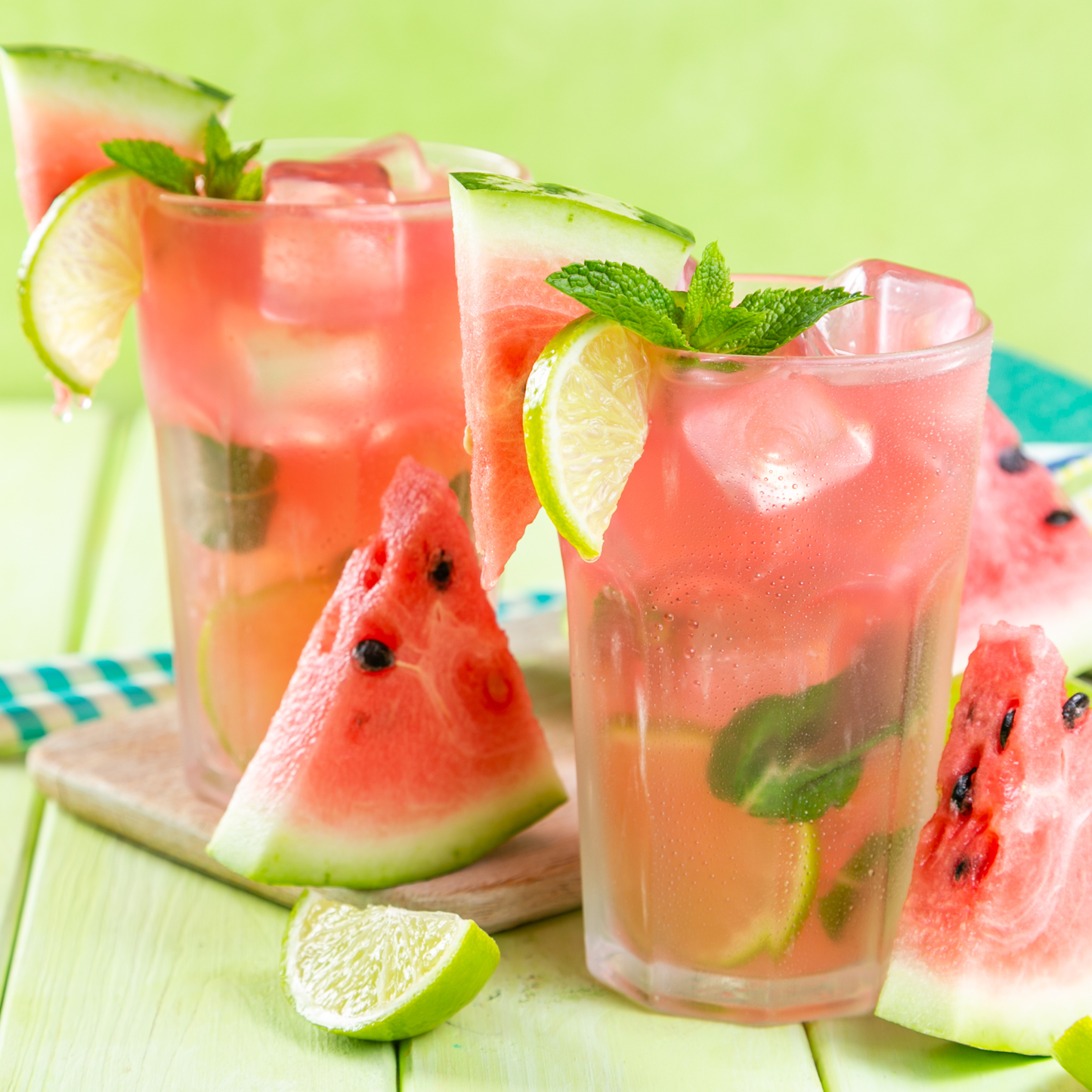 Three glasses of watermelon lemonade with slices of watermelon and lime on a green background
