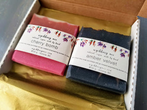 Wychbury Ave soap subscription bars in Cherry Bomb and Amber Velvet scents side by side in a Soapscription box. 